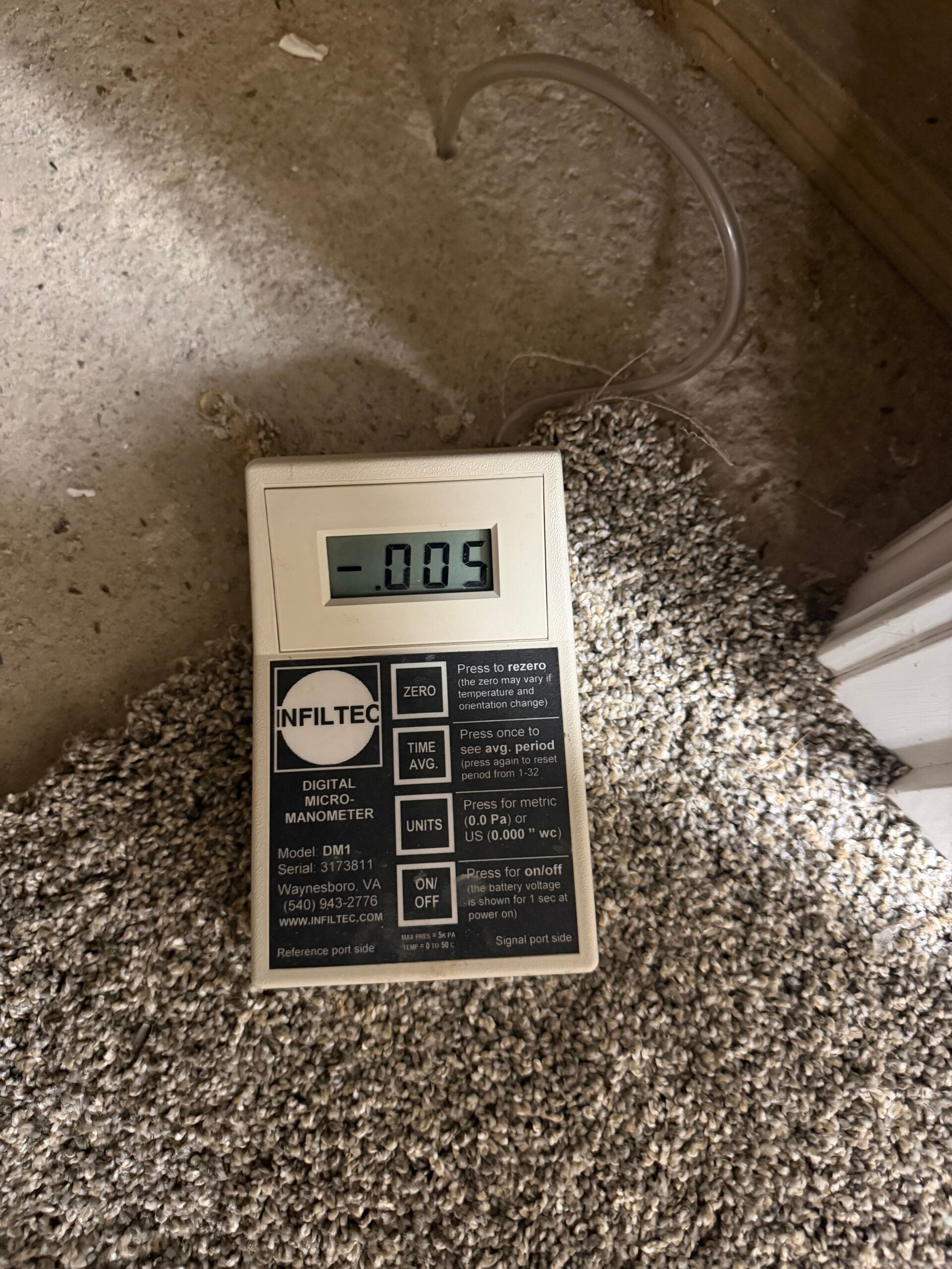 Infiltec DM1 digital micromanometer displaying a negative pressure reading during pressure field extension testing for radon mitigation in Oak Ridge Tennessee