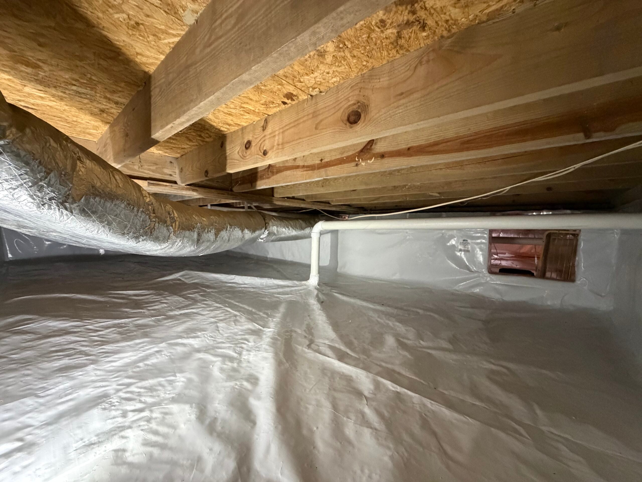 Crawlspace vapor intrusion mitigation with a sealed white vapor barrier and PVC piping installed by Rn86 Solutions