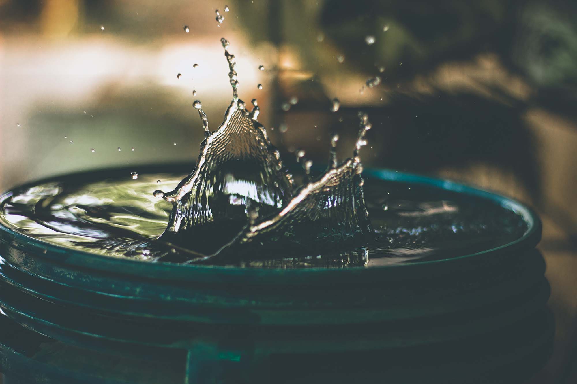 Water splashing in a dark teal container, representing well water radon testing